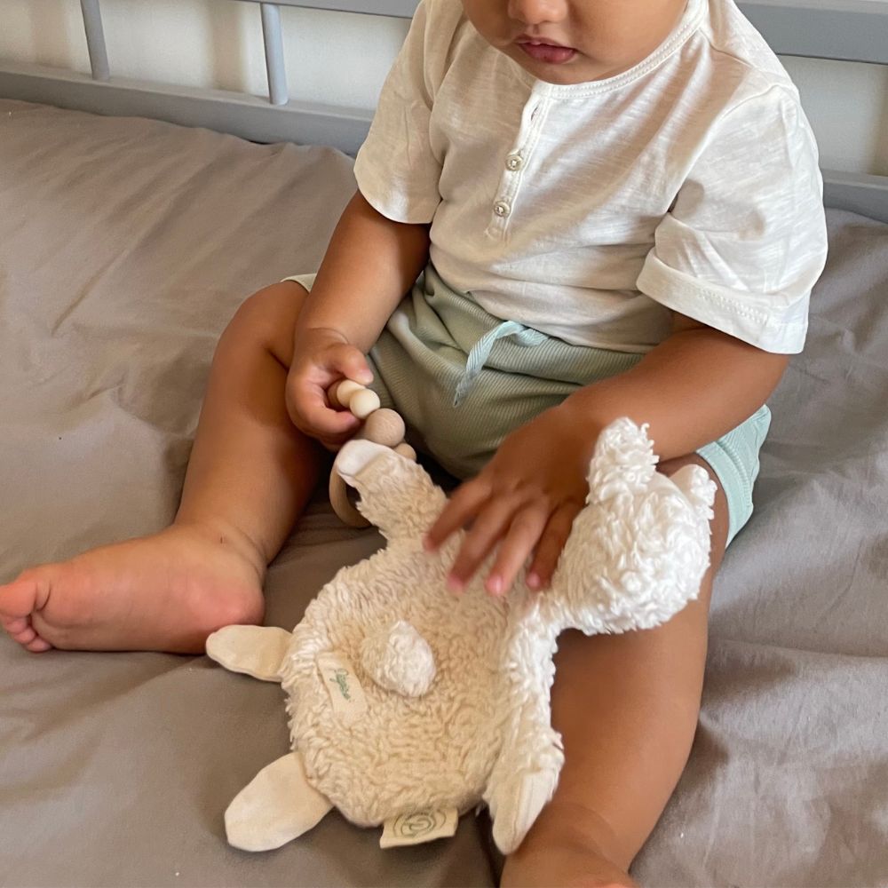 bébé jouant avec un doudou bio Pitigaïa dans une chambre